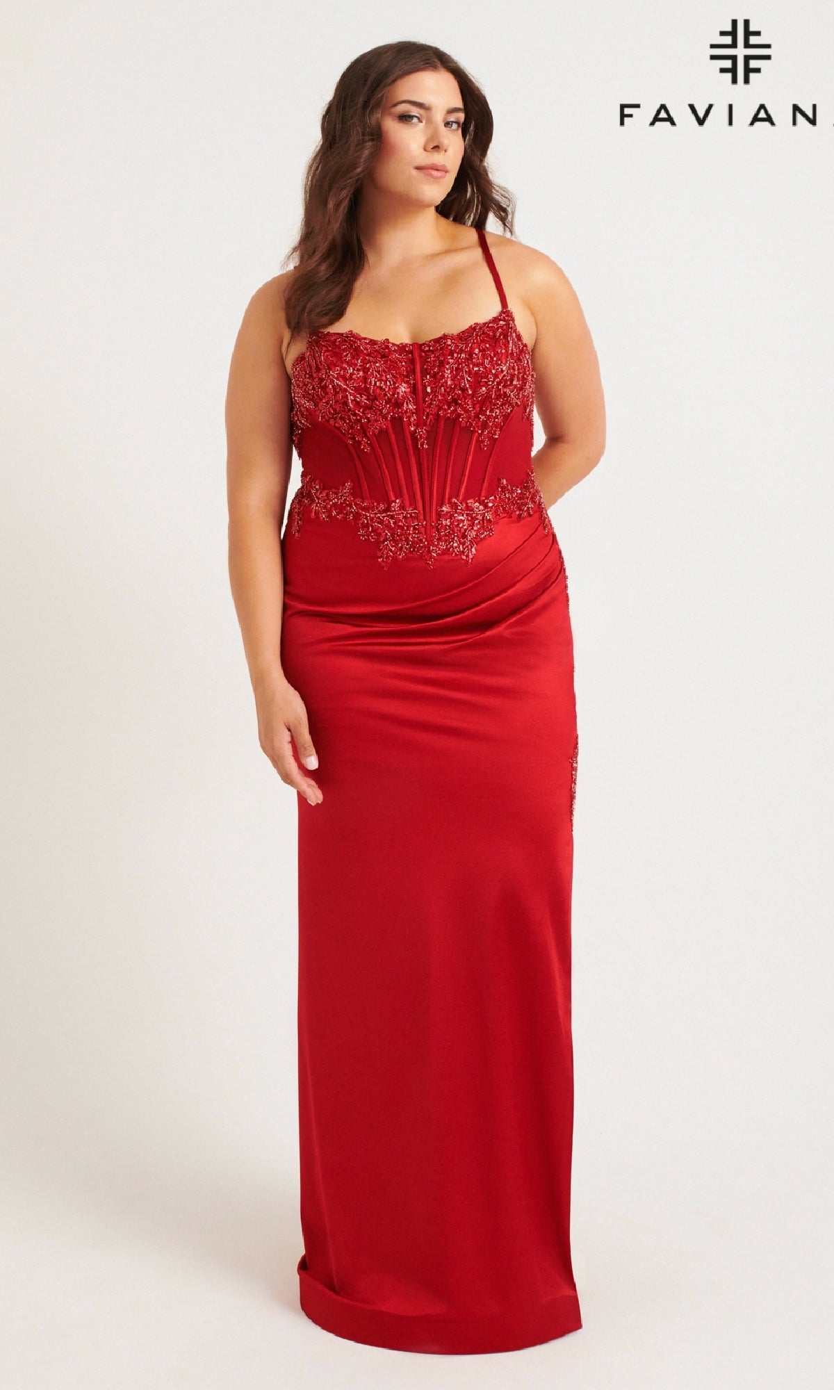 A woman models the Faviana 9592 Long Plus-Size Prom Dress—a fitted, floor-length red gown with a beaded corset bodice and lace details—standing against a plain background beside the Faviana logo.
